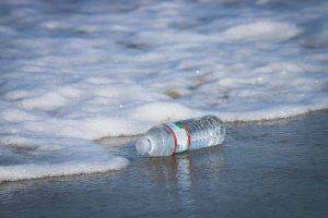 Plastic water bottle laying on the shore near snow in winter